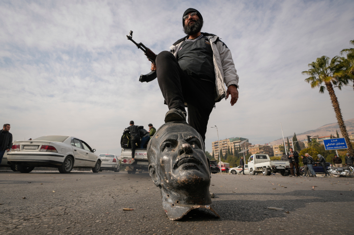 A rebel fighter steps triumphantly on a broken bust of late Syrian dictator Hafez Al-Assad. Israel’s crippling of Iran and its proxies facilitated the overthrow of the Assad regime, created a new balance of power in the Middle East, and creates an opportunity to reshape the region.